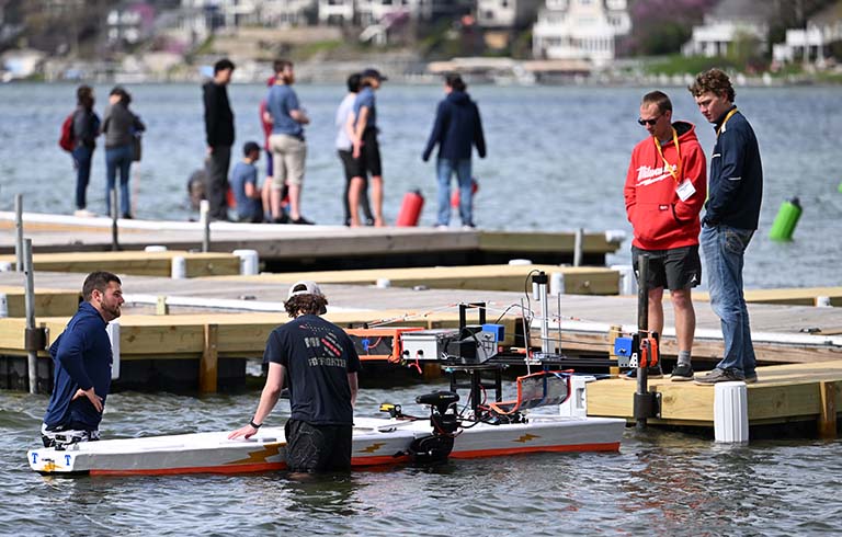 Students on a dock and in the water preparing their LPV for competition