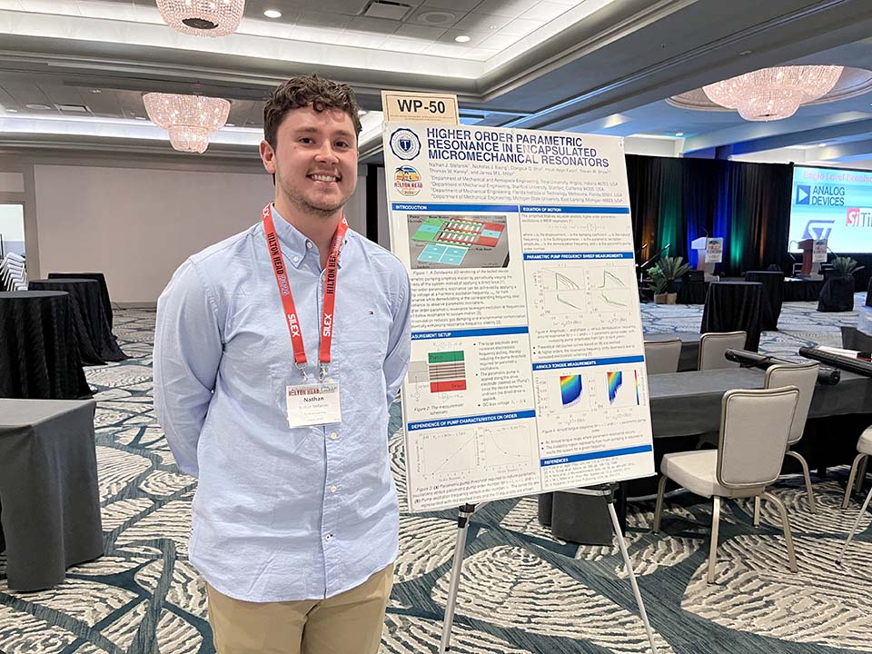 Student standing to left of research poster
