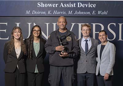 Four students with paramedic Ben Masten, who is holding the prosthetic they developed for him